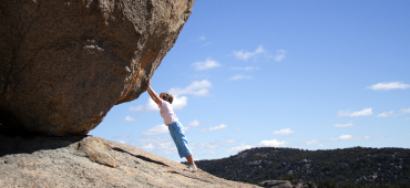 En lite pojke håller upp en stor sten/bergvägg